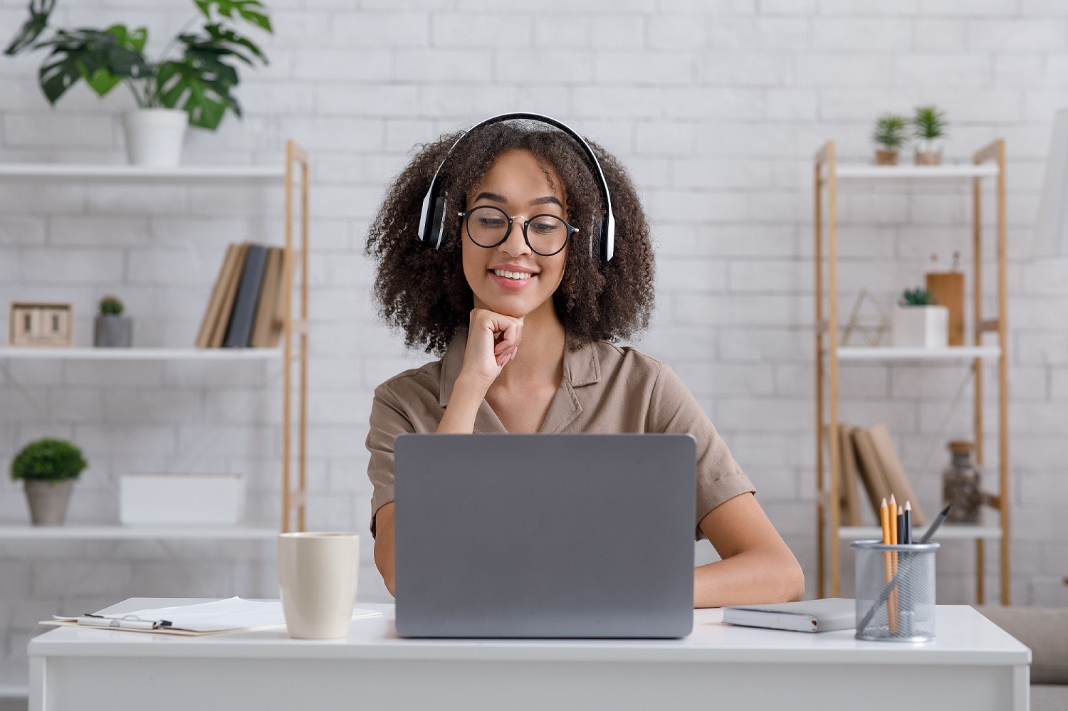 A girl with big headphones working on her laptop.