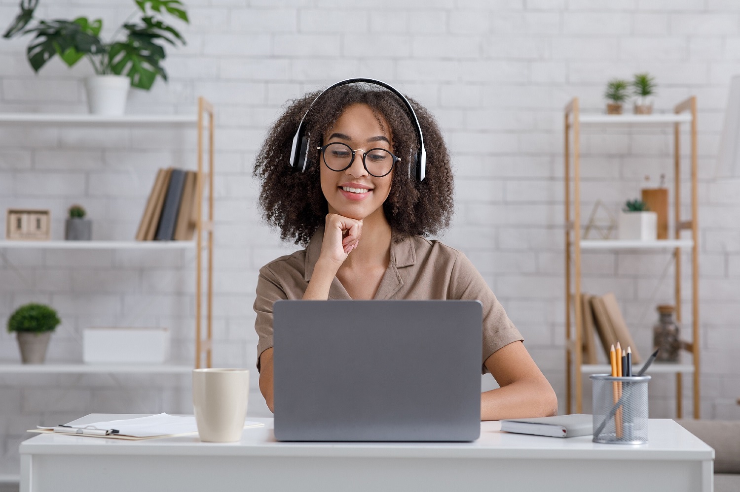 A girl with big headphones working on her laptop. 