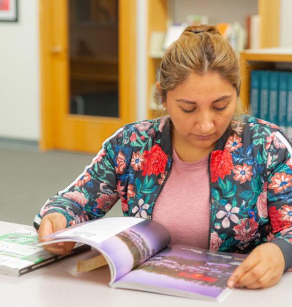 A woman reading a magazine in Saint Augustine College's library.