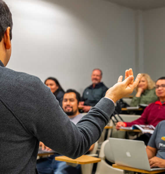 Someone conducting a lecture to a full classroom.