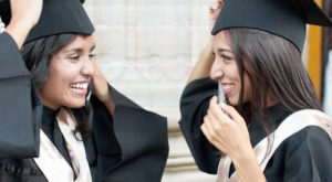 Two female graduates smiling at each other