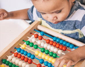 A toddler playing with an abacus.