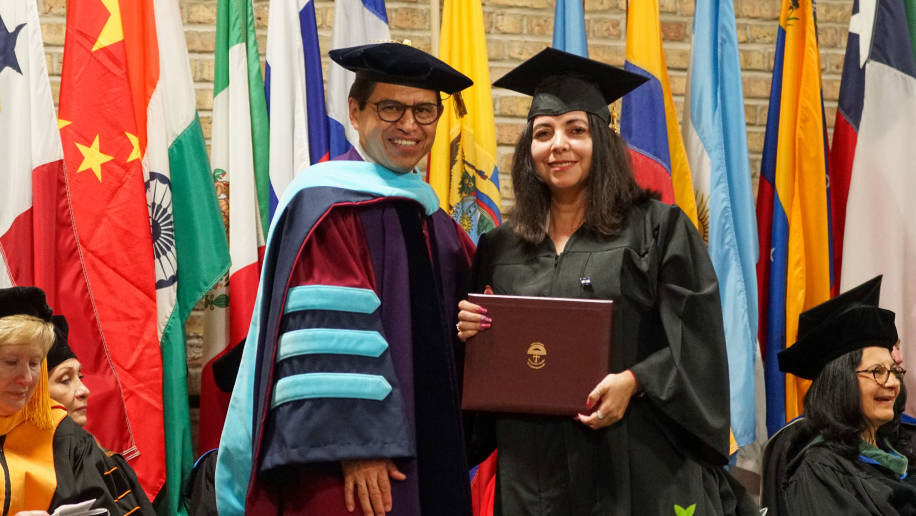 Student presenting her degree alongside the president of Saint Augustine college. 
