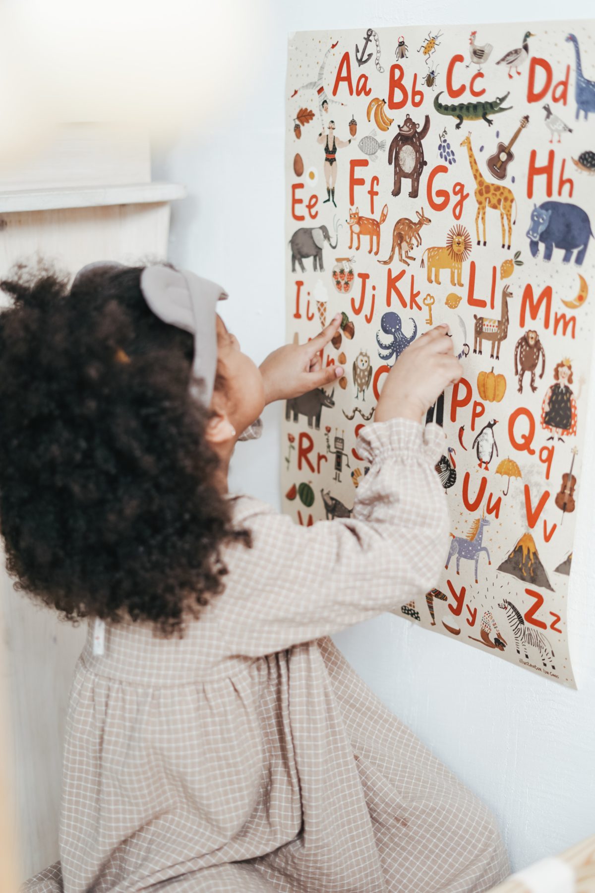A young child looking at a poster of the alphabet. 