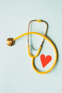 A yellow stethoscope wrapped around a paper heart.