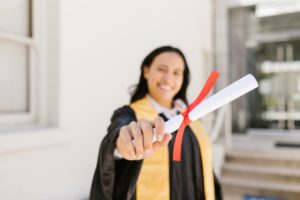 A young woman in a gown holding a degree.