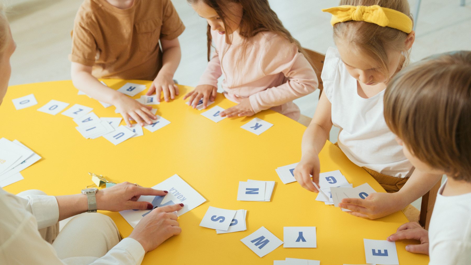 A group of toddlers holding letters from the alphabet. 