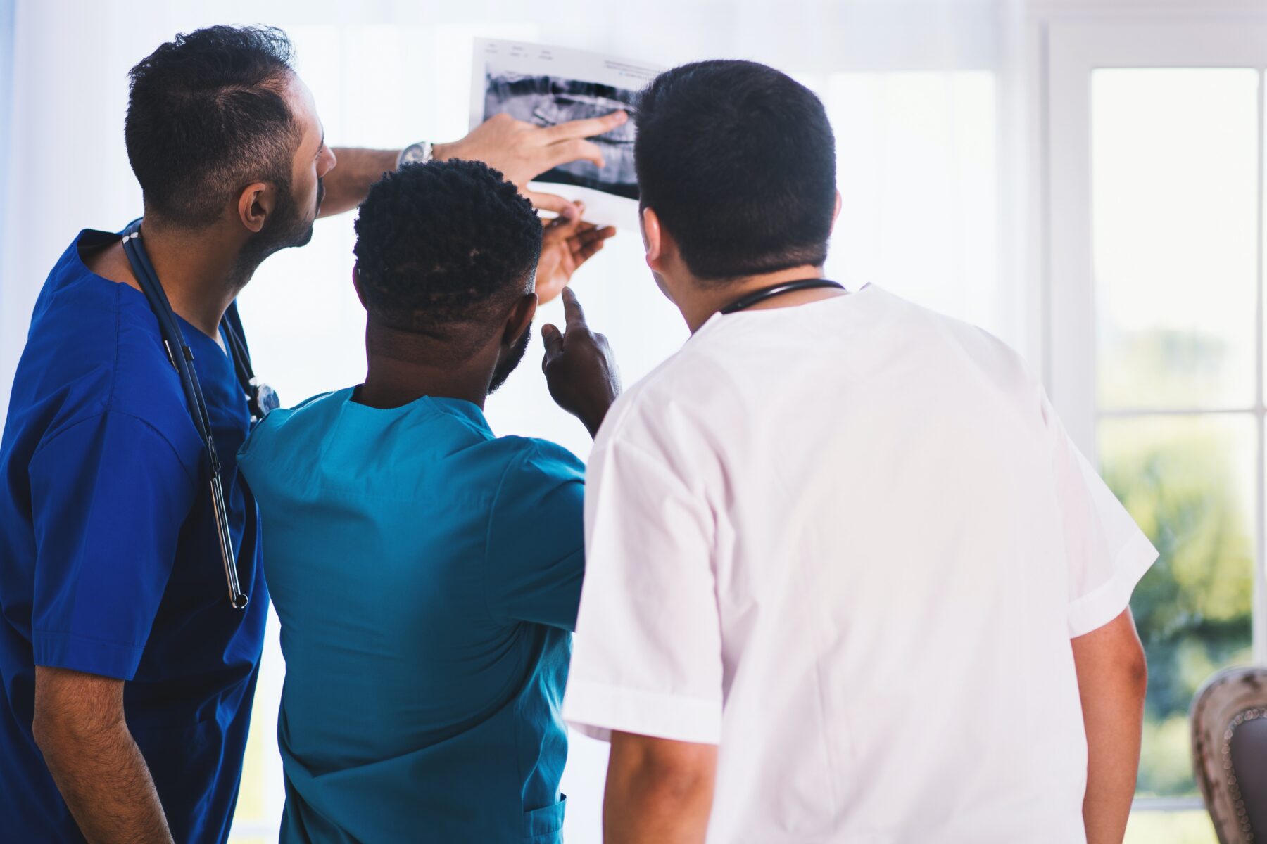 Three medical professionals examining x-rays.