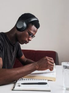 A young man studying with a notebook, pen, and book.